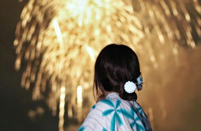 Woman in yukata watches fireworks display