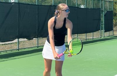 UW-Stout tennis player prepares to serve during a match on an outdoor court at the USTA National Campus.