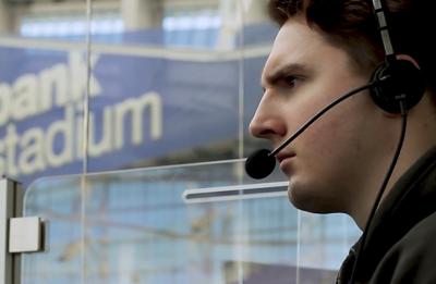 A person wearing a headset works from a broadcast position inside a stadium, focused on event production.