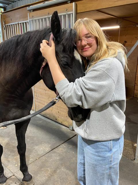 Woman stands with horse